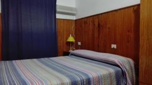 ein Schlafzimmer mit einem Bett mit einer gestreiften Decke in der Unterkunft Hotel Residencial Casal in La Paz