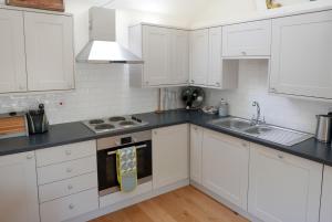 a white kitchen with white cabinets and a sink at Bakers Court in East Rudham