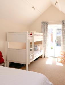 ein Schlafzimmer mit einem weißen Etagenbett und einem Fenster in der Unterkunft Bakers Court in East Rudham