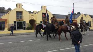 
a large group of people riding horses down a street at The Anchor Inn Beachfront Motel in Kaikoura
