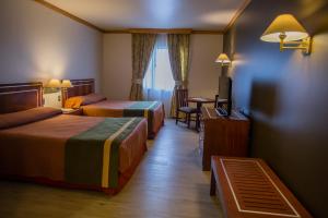 a hotel room with two beds and a table at Hotel Diego de Almagro Puerto Montt in Puerto Montt