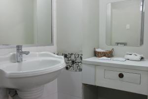 a white bathroom with a sink and a mirror at Aristos Puebla in Puebla