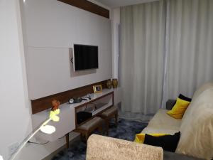 a hotel room with a desk and a tv on the wall at Apartamento Residencial Julia in Guarapari