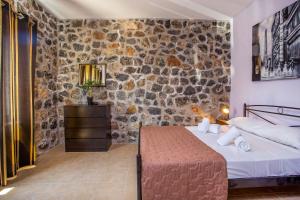 a bedroom with a bed and a stone wall at Villa Helios in Kalathos