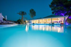 una piscina por la noche con un edificio en Coral Blue Beach Hotel Gerakini, en Gerakini