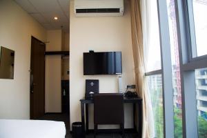 um quarto com uma secretária e uma televisão na parede em Sakura Hotel 2 em Hanói