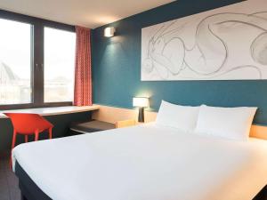 ein Schlafzimmer mit einem großen weißen Bett und einem roten Stuhl in der Unterkunft ibis Liège Centre Opéra in Lüttich
