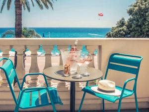 - une table avec 2 chaises et des verres à vin sur le balcon dans l'établissement Mercure Nice Marché Aux Fleurs, à Nice