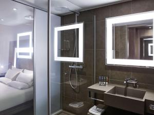 a bathroom with a large mirror and a television at Novotel Manchester Centre in Manchester