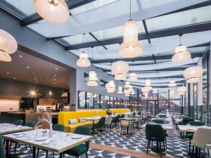 une salle à manger avec des tables, des chaises et des lumières dans l'établissement Hotel Century Old Town Prague - MGallery Hotel Collection, à Prague