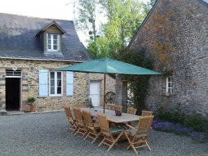 a table and chairs with an umbrella in front of a building at Le Moulin d'Hys in La Cropte