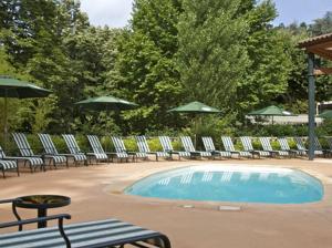 einen Pool mit Stühlen, Tischen und Sonnenschirmen in der Unterkunft Grand Hotel Des Bains in Vals-les-Bains