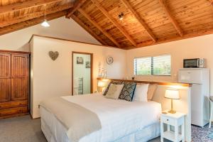 a bedroom with a large bed and a wooden ceiling at Harbour View Cottage Bay of Islands in Opua