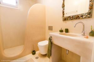 ein Badezimmer mit einem Waschbecken, einem WC und einem Spiegel in der Unterkunft Aerides Villas in Naxos Chora