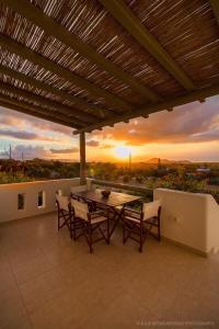 eine Terrasse mit einem Tisch und Stühlen sowie einem Sonnenuntergang in der Unterkunft Aerides Villas in Naxos Chora