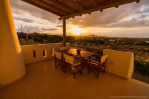 a table and chairs on a balcony with the sunset at Aerides Villas in Naxos Chora