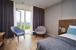 una camera d'albergo con un letto e due sedie e una finestra di Hotel Berg by Keflavik Airport a Keflavík