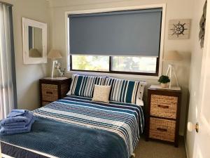 a bedroom with a bed and a large window at Lakeview Cottage in Forster