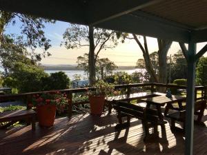a wooden deck with a table and benches on it at Lakeview Cottage in Forster