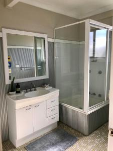 a bathroom with a tub and a sink and a shower at Lakeview Cottage in Forster