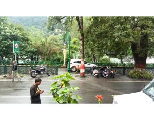 Un homme debout sous la pluie dans un parking avec des motos dans l'établissement Hotel Marino, à Nainital