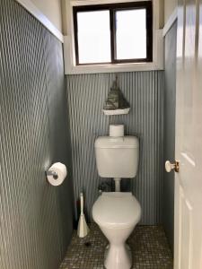 a bathroom with a toilet with a window above it at Lakeview Cottage in Forster