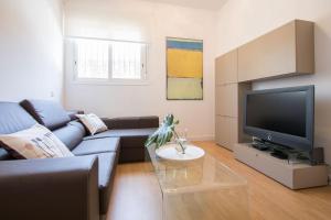 a living room with a blue couch and a tv at Murallas de Sevilla Apartamento con garaje 4 pax in Seville