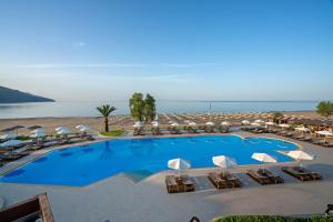 
a beach with a pool, chairs, and tables at Pilot Beach Resort in Georgioupolis
