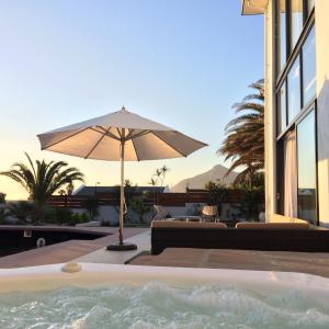 a patio with an umbrella and a hot tub at Cape White Villa in Capri Village