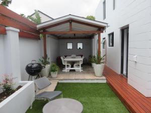un patio con mesa y sillas en una terraza en Cape White Villa, en Crawley