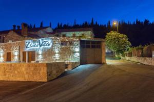 a building with lights on the side of it at night at Konavle Apartments Zlatovisce in Gruda