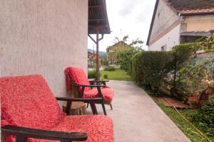 巴伊納巴什塔的住宿－Drina - Bajina Basta，两把红色椅子坐在房子的一侧