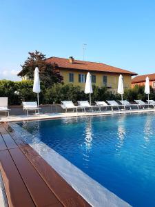 una piscina con sedie a sdraio e ombrelloni bianchi di Locanda Ferro UNO, Golf Città di Asti ad Asti