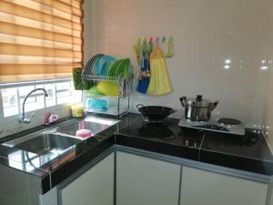 a kitchen counter with a sink and a stove at Faeyz Homestay Pertam Jaya in Malacca