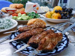 uma mesa coberta com pratos de comida com carne em espetos em Diyor Hostel em Bucara