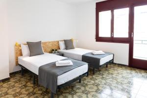 a room with two beds and a couch and windows at Duc Allotjament in La Seu d'Urgell