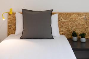 una cama con una almohada gris encima en Duc Allotjament en La Seu d'Urgell