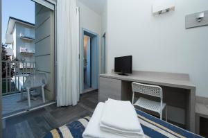 リミニにあるHotel Aquila Azzurraのリビングルーム(テレビ、デスク、椅子付)