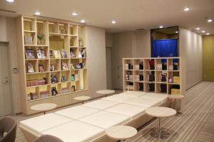 een wachtkamer met een tafel en stoelen en boekenplanken bij JR Inn Sapporo-eki Minami-guchi in Sapporo