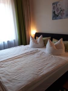 - un lit avec des draps et des oreillers blancs dans une chambre dans l'établissement Danka, à Neukirchen beim Heiligen Blut