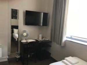 a hotel room with a desk with a television on the wall at Hatfield Lodge in Lowestoft