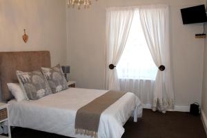 a bedroom with a bed and a window at Boer & Brit in Graaff-Reinet
