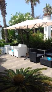 a patio with white chairs and an umbrella at Le Pinède in Licola