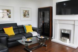 a living room with a black leather couch and a fireplace at The Marlfield in Bellshill