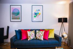 a blue couch with colorful pillows in a living room at Superior 2 bedroom Apartments in Woolwich