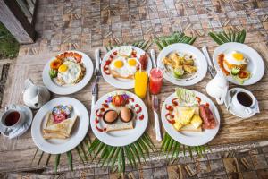 een tafel met borden ontbijtproducten erop bij The Syron Huts Lembongan in Nusa Lembongan