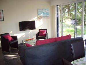 een woonkamer met een bank en stoelen en een tv bij Tivoli Gardens (Hertoge) in Bredene
