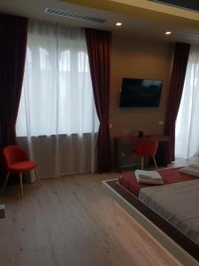 a hotel room with a bed and a tv and curtains at Th Luxury Rooms & Apartment in Giardini Naxos