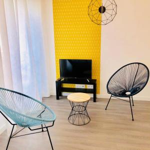 sala de estar con 2 sillas y TV en BtoBed - Paris Nord Villepinte en Villepinte