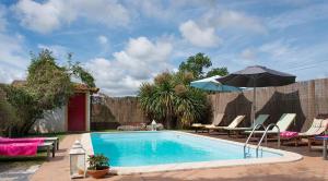 uma piscina com cadeiras e um guarda-sol em Casa Ci em Vila Franca